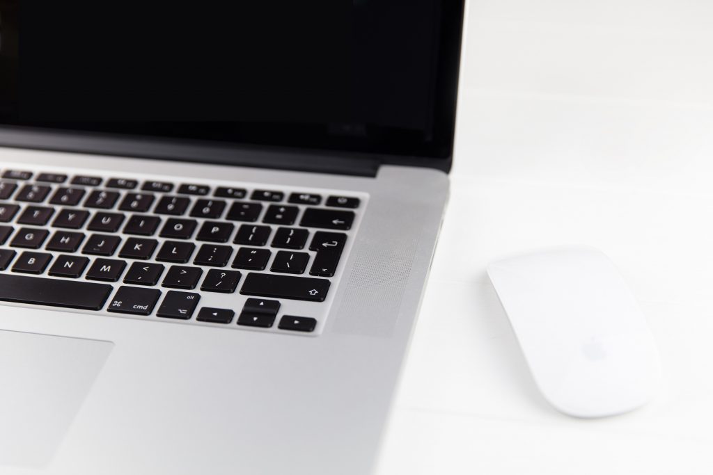 Un ordenador portátil con un ratón en una mesa blanca.