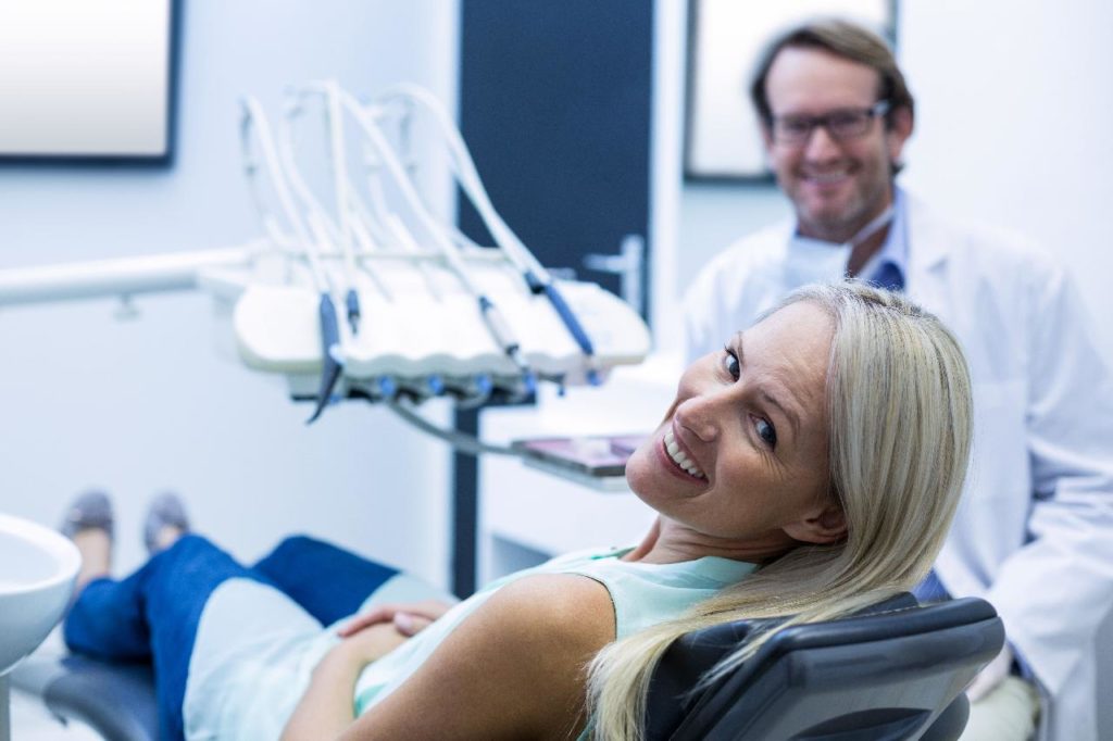 Una mujer está sentada en el sillón de un dentista en una clínica dental internacional.