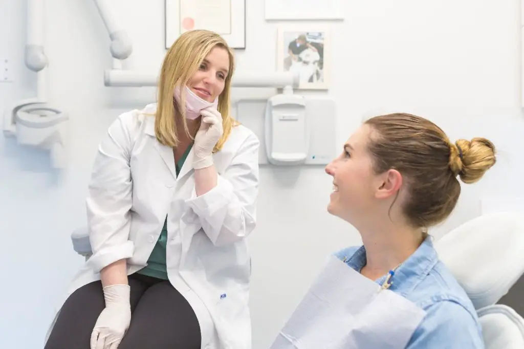 Una mujer conversaba dentro de una clínica dental enfatizando el servicio al cliente.