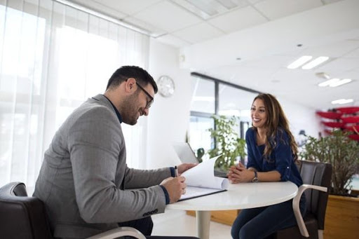 Un hombre y una mujer discutiendo prácticas de contratación en una oficina grande.