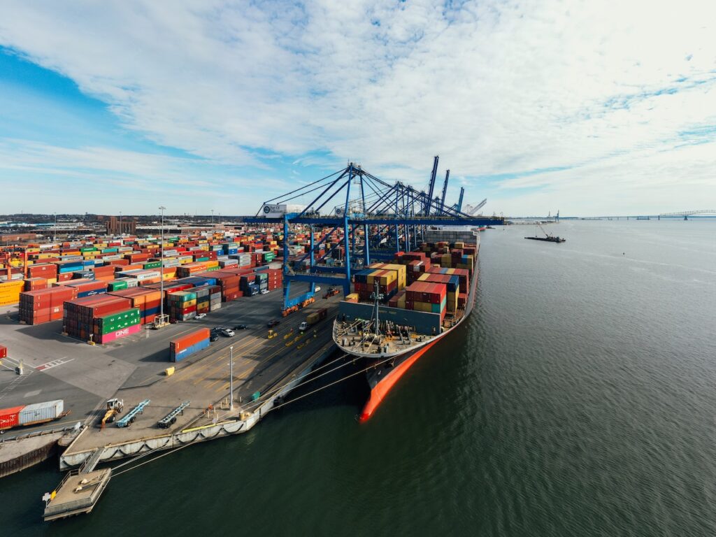 Una vista aérea de un buque portacontenedores atracado en un puerto que muestra la importancia del transporte marítimo en el comercio internacional.