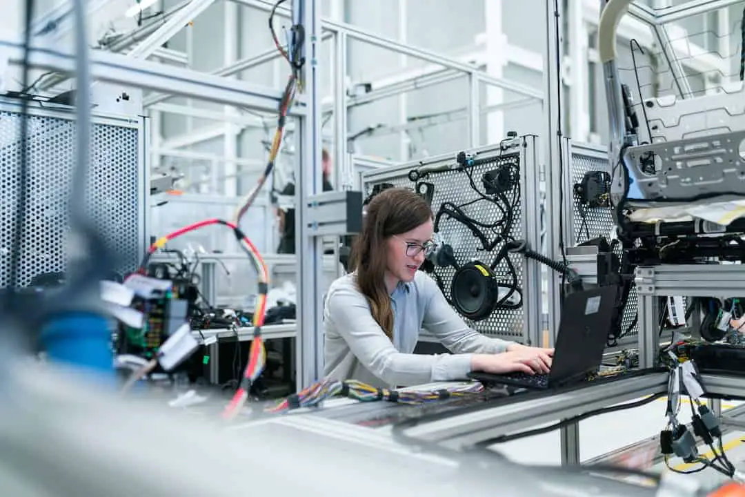 Una mujer trabajando con una computadora portátil en una fábrica.