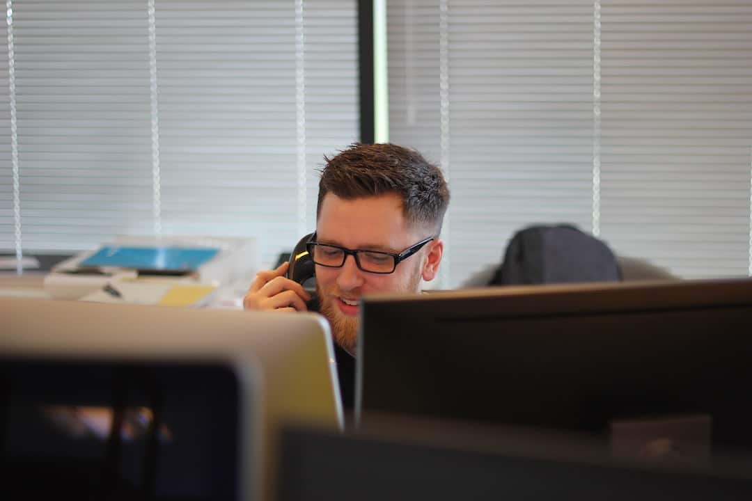 Un hombre hablando por teléfono frente a una computadora.