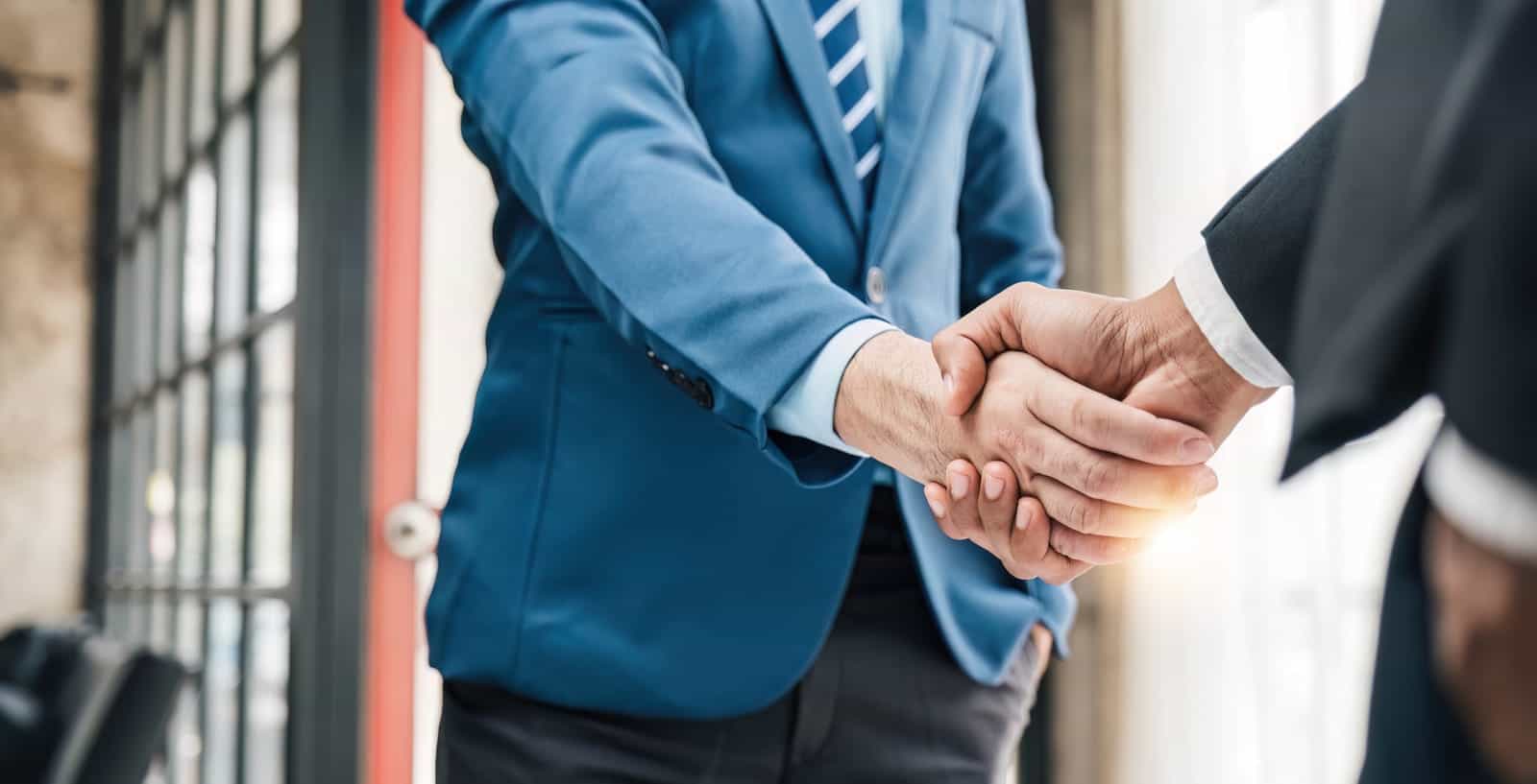 Dos empresarios dándose la mano en una oficina.