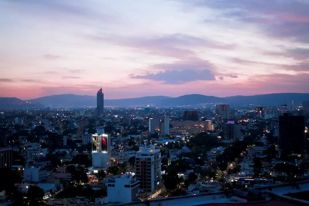 Una ciudad al anochecer con las montañas al fondo. Ideas de Negocios Rentables en Guadalajara