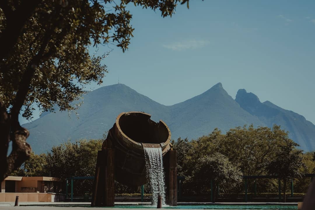Una fuente de agua en medio de una piscina con montañas al fondo. Ideas de Negocios Rentables en Monterrey