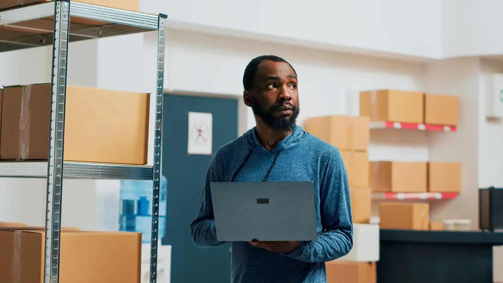 Un hombre en un almacén sosteniendo una computadora portátil.