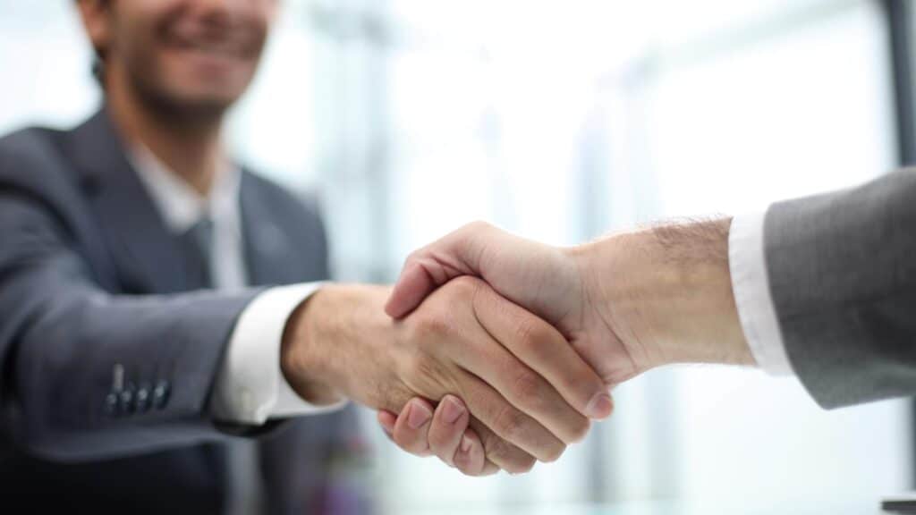 Dos hombres de negocios se dan la mano frente a una oficina.