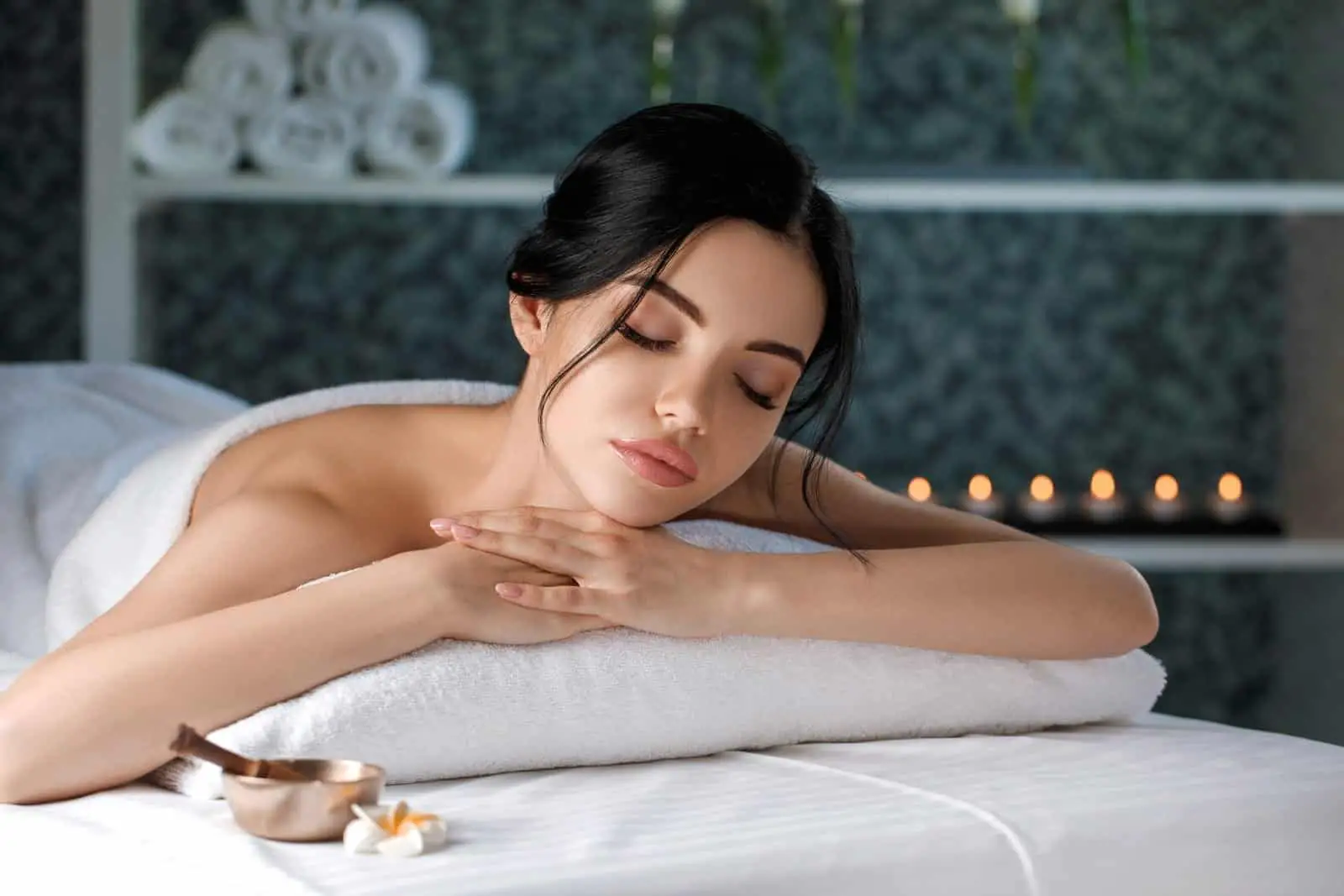 Una mujer relajándose en una camilla de masaje en un spa.