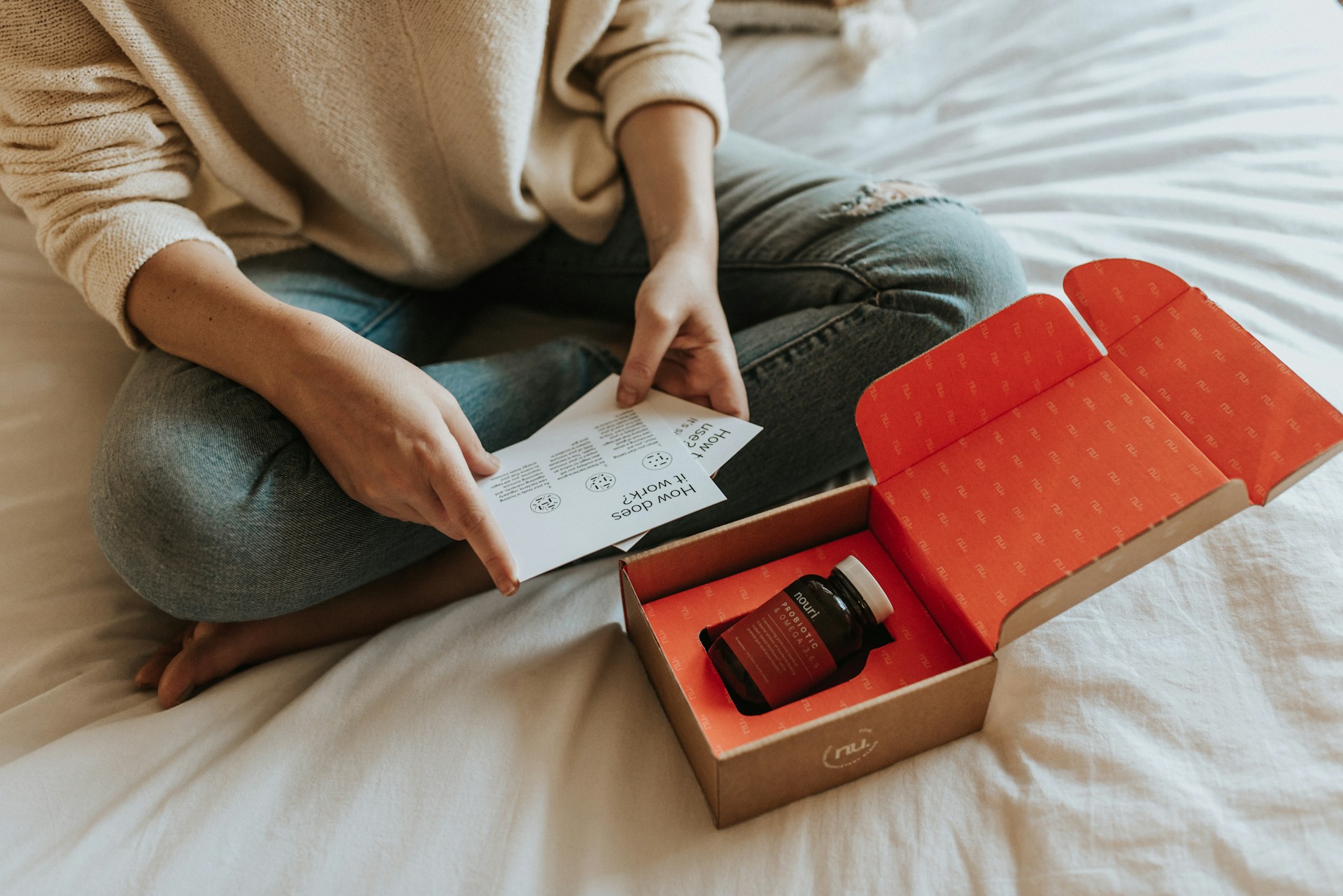Una persona sentada en una cama y abriendo un paquete.